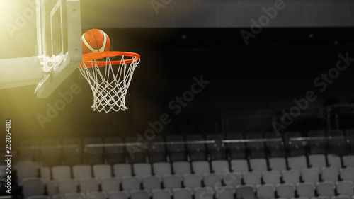 Basketball ball flies into the basketball hoop on the background of the stands of the sports complex