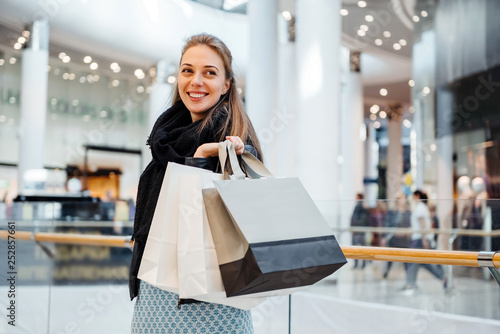 Caucasian girl in shopping mall holding shopping bags. Girl on shopping