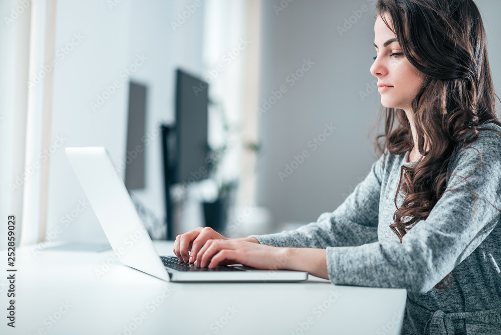 Young businesswoman working on laptop, side view. Young businesswoman working on laptop, side view.