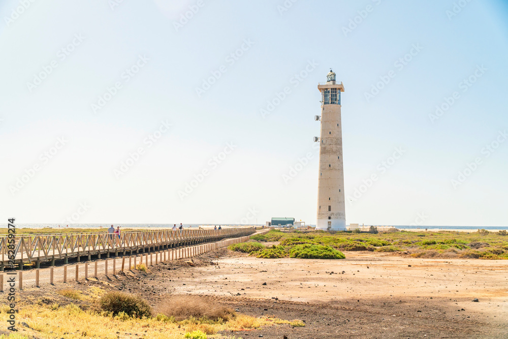 Obraz premium Lighthouse and wooden bridge with tourists in Morro Jable, Fuerteventura, Spain