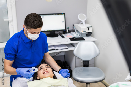 Man dentist and woman patient during the process of teeth whitening in dental clinic