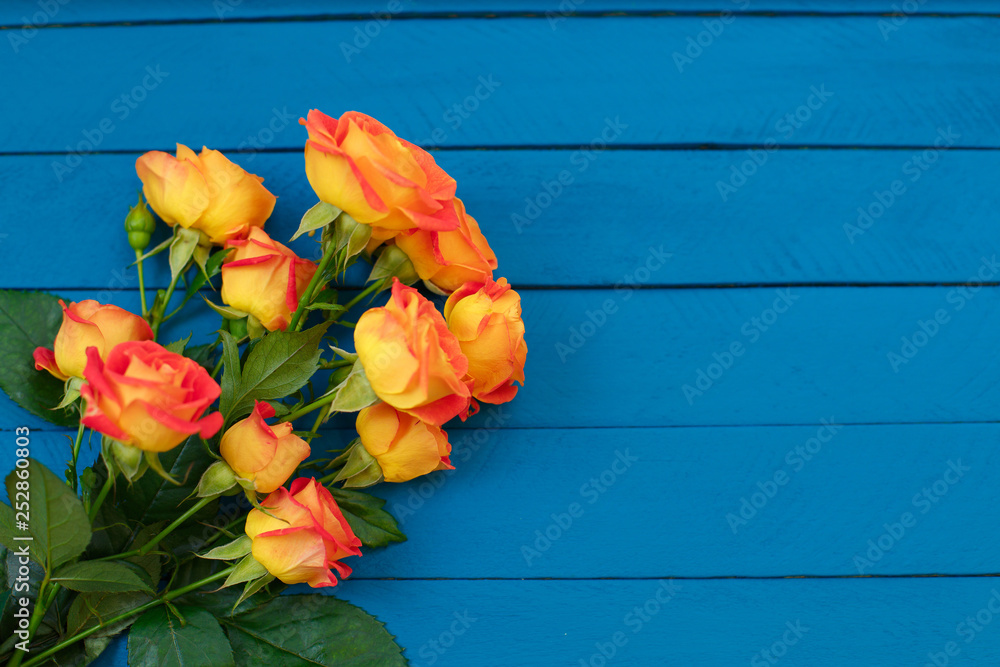 Background of a bouquet of beautiful fresh vivid orange roses tinged with red for celebrating an anniversary, birthday or Mothers Day