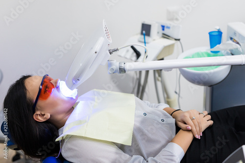 Fototapeta Naklejka Na Ścianę i Meble -  Laser bleaching teeth at dantist room. Teeth whitening for woman. Bleaching of the teeth at dentist clinic.
