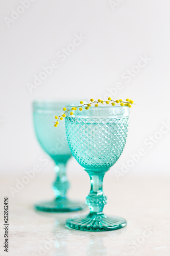 Blue Vintage Goblets and yellow mimosa flowers . Wineglasses on whight background.