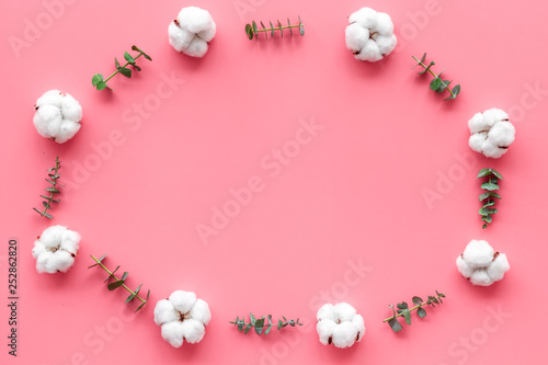 Flowers frame with fresh eucalyptus branches and cotton on pink background top view copy space