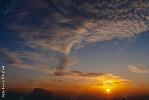 Sunny shine on clouds. Wonderful vivid dawn. Beautiful calm orange sunset. Scenic urban sunrise. Amazing cloudy sky. Picturesque sundown. Atmospheric cloudscape. Circle of sun above city horizon.