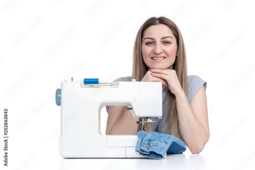 Young woman sews on a sewing machine, isolated on white background 