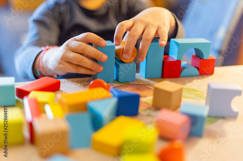 a child plays with colored wooden blocks at home.kid plays and builds buildings and towers with wooden colored blocks.