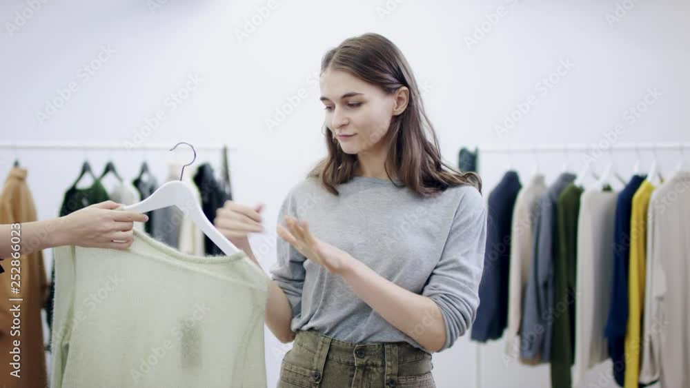 Young attractive woman posing with a swater that someone passed her in a clothing toom Young attractive woman posing with a swater that someone passed her in a clothing toom