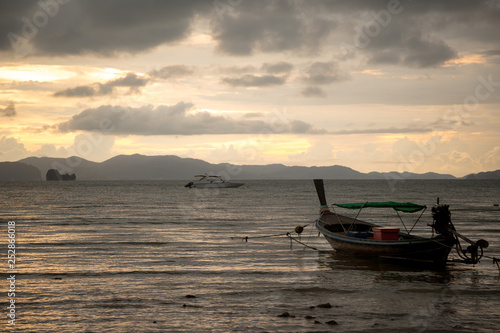 Beautiful sunset on the sea with traditional thai fishing longtail boats