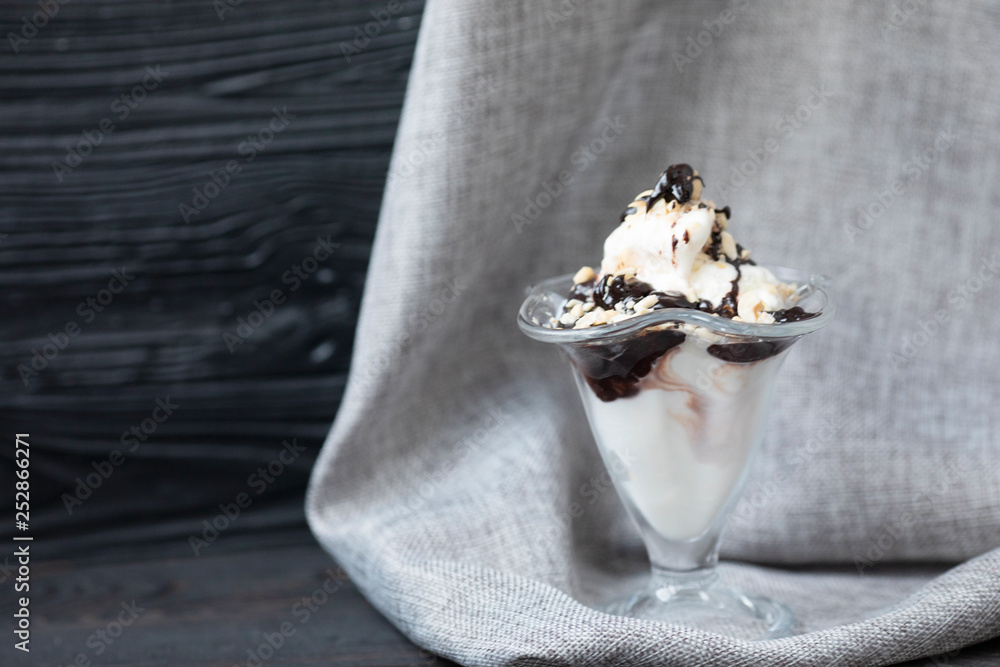 Ice cream cup with cream, topping and cookies on grey background.