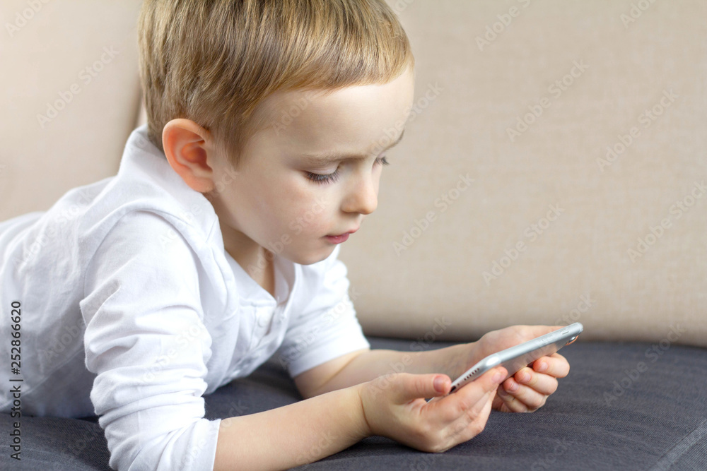 Cute little boy using smartphone voice application at home. Happy smart child using mobile app. Education, technology and fun concept. Cute little boy using smartphone voice application at home. Happy smart child using mobile app. Education, technology and fun concept.