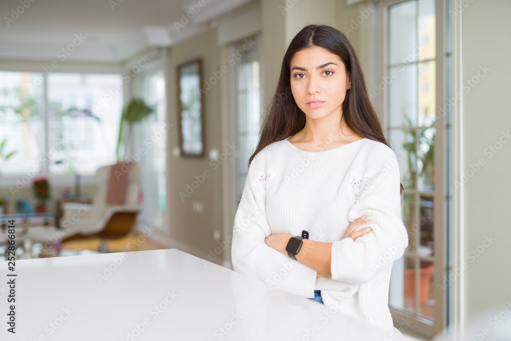 Young beautiful woman at home on white table skeptic and nervous, disapproving expression on face with crossed arms. Negative person. Young beautiful woman at home on white table skeptic and nervous, disapproving expression on face with crossed arms. Negative person.