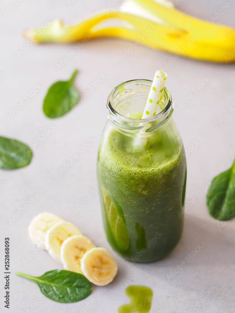 Grüner Smoothie mit Blattspinat und Banane in einer Glasflasche mit Strohalm Grüner Smoothie mit Blattspinat und Banane in einer Glasflasche mit Strohalm