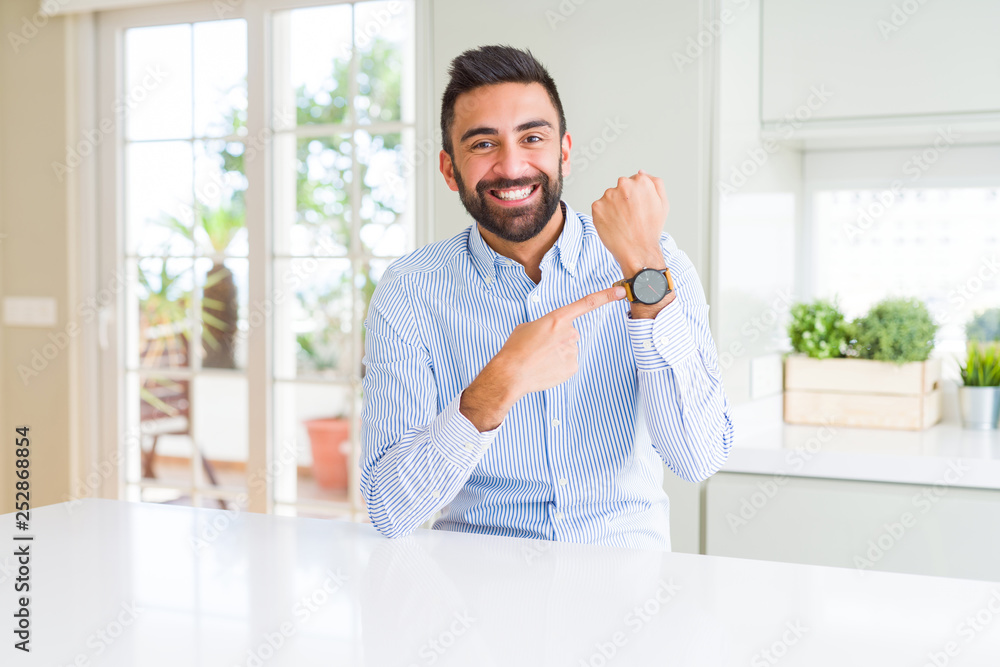 Handsome hispanic business man In hurry pointing to watch time, impatience, upset and angry for deadline delay