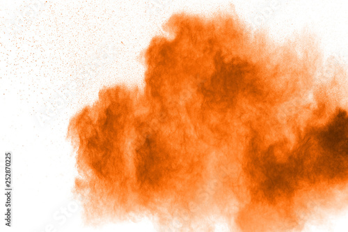 Abstract yellow orange powder explosion on white background. Freeze motion of orange dust particles splash.