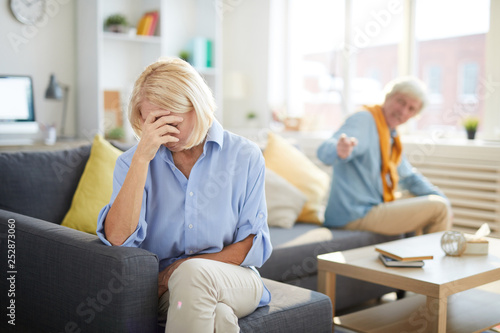 Portrait of modern senior couple fighting focus on crying senior woman in foreground, copy space