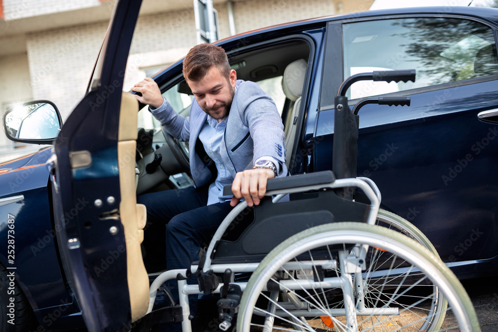 Young handicapped man reaching for his wheelchair Young handicapped man reaching for his wheelchair