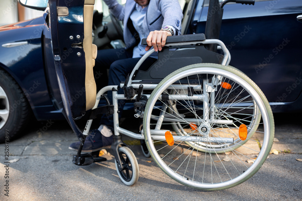 Young handicapped man reaching for his wheelchair Young handicapped man reaching for his wheelchair