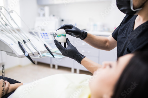 Young Man dentist holiding denture yawn for demonstarion in dental clinic