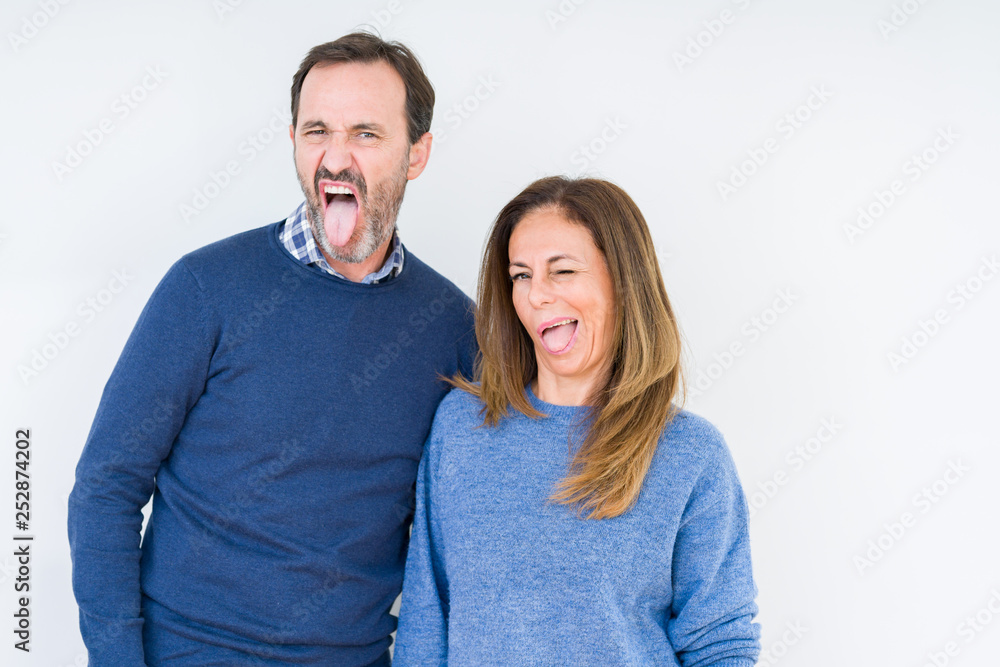 Beautiful middle age couple in love over isolated background sticking tongue out happy with funny expression. Emotion concept. Beautiful middle age couple in love over isolated background sticking tongue out happy with funny expression. Emotion concept.