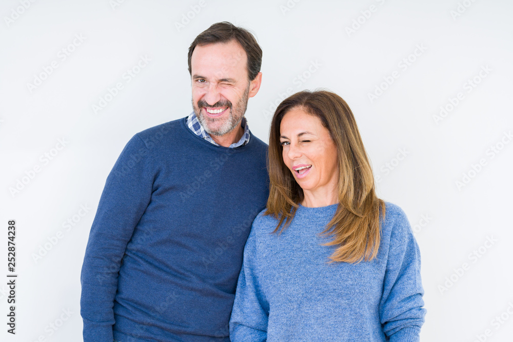 Beautiful middle age couple in love over isolated background winking looking at the camera with sexy expression, cheerful and happy face.