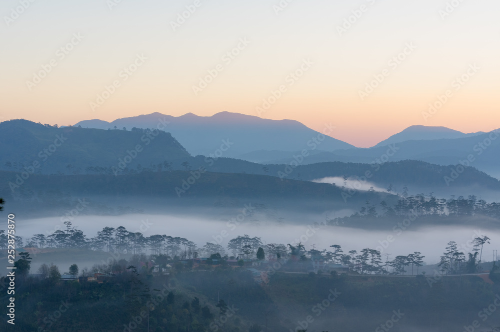 Fog cover small village at the foot mountains with the magical of light at dawn