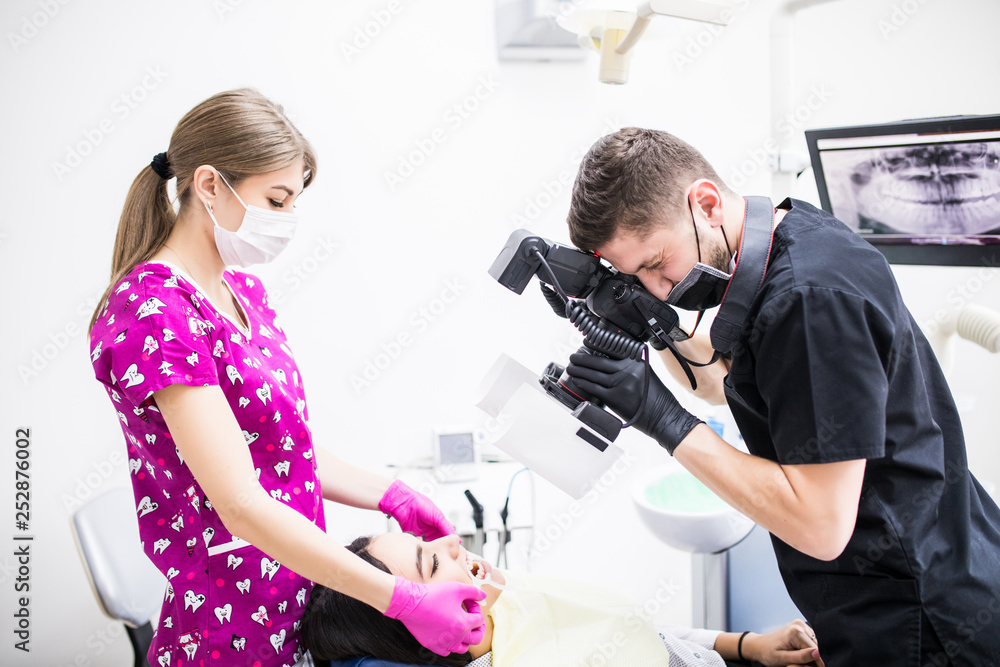 Close up of young man dentist taking picture of teeth of female patient in dental clinic. Close up of young man dentist taking picture of teeth of female patient in dental clinic.