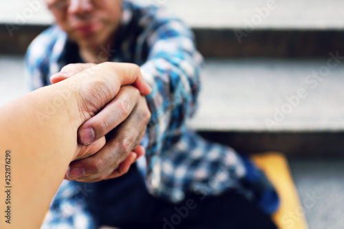 Close-up handshake for help homeless man on walking street in the capital city.