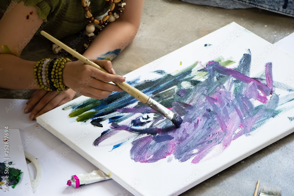 Fototapeta premium Hand of young artist painting on canvas,doing art work,at studio