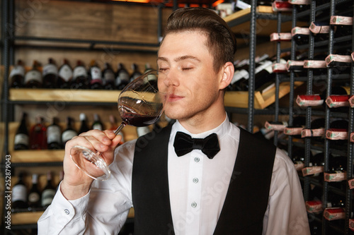 What a rich aroma. Handsome sommelier enjoying wine aroma from the glass smiling with his eyes closed