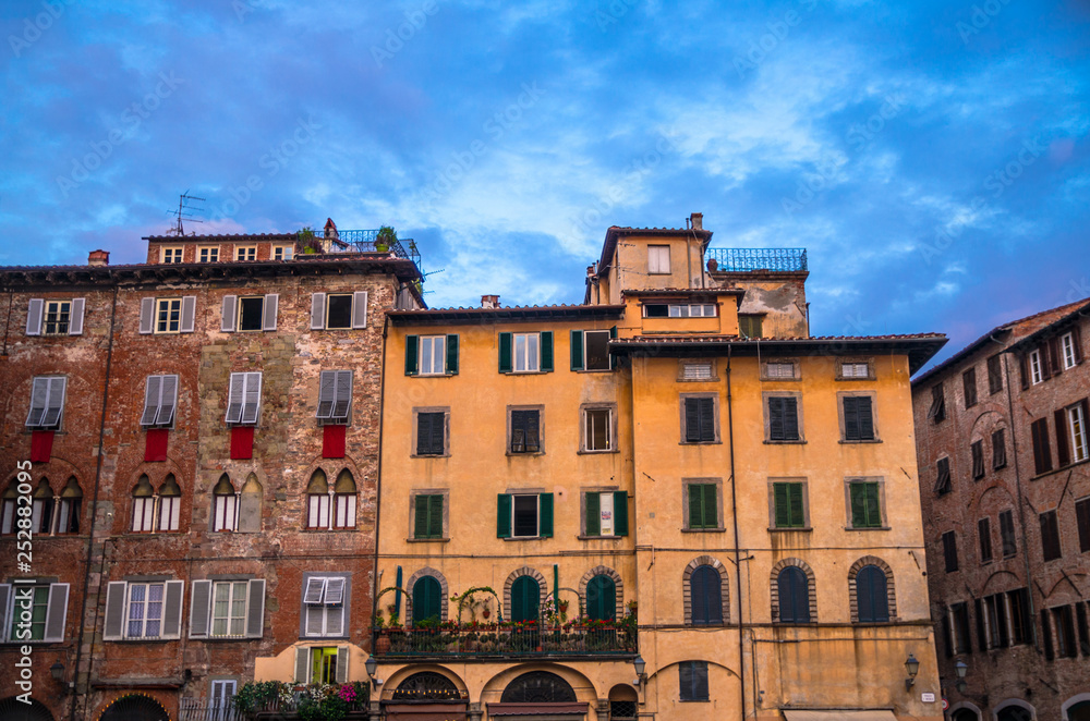 Typical traditional italian buildings on Piazza San Michele square in historical centre of old medieval town Lucca, evening view, Tuscany, Italy