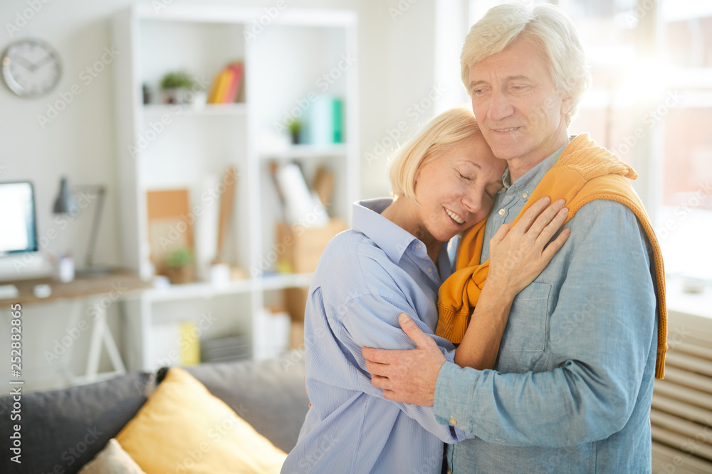 Waist up portrait of happy senior couple embracing tenderly at home lit by sunlight Waist up portrait of happy senior couple embracing tenderly at home lit by sunlight