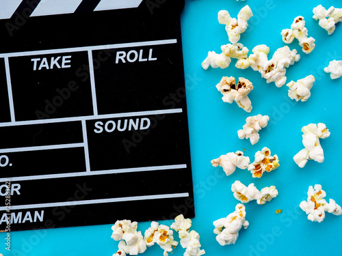 Popcorn and clapperboard on blue background. the concept of movie, film, entertainment, advertising photo