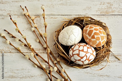 Slika na platnu Delightful Easter decoration with eggs in the nest and willow twigs on white woo