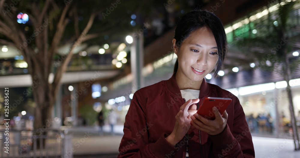 Woman check on cellphone in city at night Woman check on cellphone in city at night