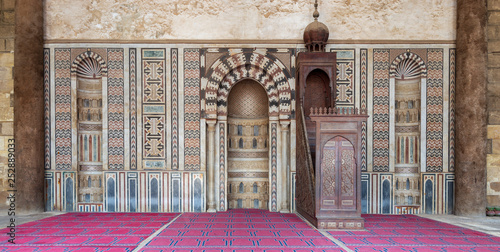 Colorful decorated marble wall with engraved Mihrab (niche) and wooden Minbar (Platform) at the Mosque of Al Nasir Mohammad Ibn Qalawun, situated in the Citadel of Cairo in Egypt photo