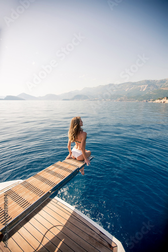 Pretty young woman relaxing on the yacht on sea at sunny day
