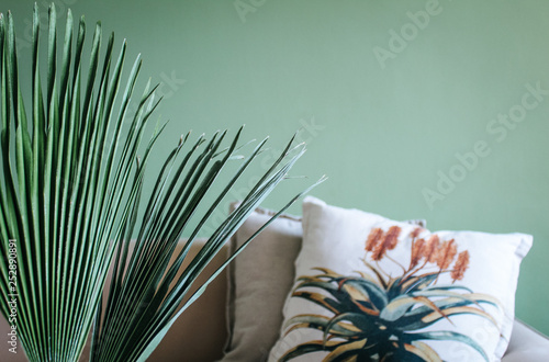 Wallpaper Mural Beige vintage couch with a botanical flower plant print cushion standing in front of a green wall. Torontodigital.ca