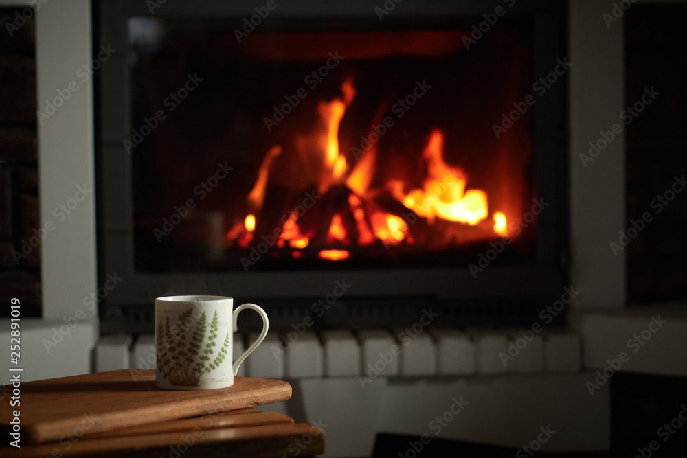 a cup of hot tea on the background of the fireplace, soft and fluffy rug, warm and cozy atmosphere a cup of hot tea on the background of the fireplace, soft and fluffy rug, warm and cozy atmosphere