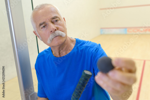 elderly squash player holding ball