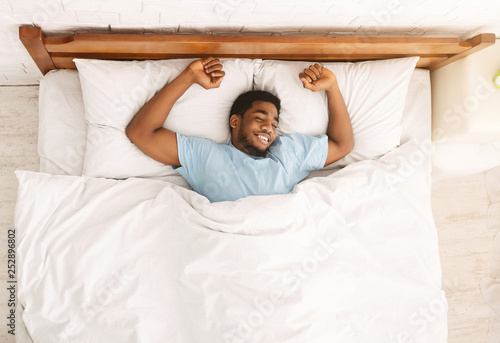 Young african-american man sleeping in bed top view