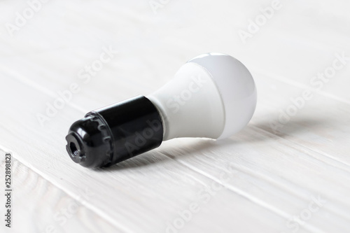 LED light in a dark base. Lies on a wooden background. white color.