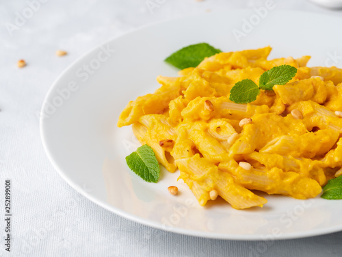 Part of Pumpkin pasta penne with parmesan on white plate, close-up, side view