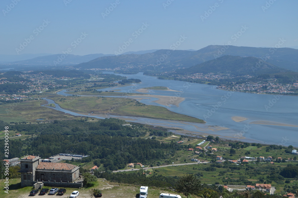 The Miño River, Forest House And Portuguese Village Of Caminha From The Castro Of Santa Tecla In The Guard. Architecture, History, Travel. August 15, 2014. La Guardia, Pontevedra, Galicia, Spain. The Miño River, Forest House And Portuguese Village Of Caminha From The Castro Of Santa Tecla In The Guard. Architecture, History, Travel. August 15, 2014. La Guardia, Pontevedra, Galicia, Spain.