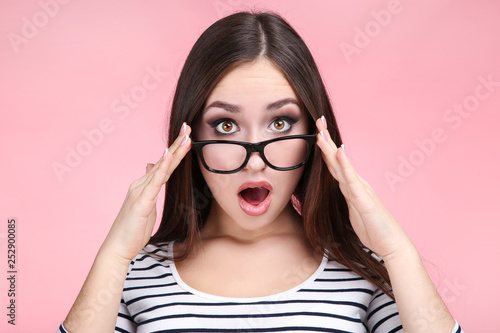 Young woman with glasses on pink background