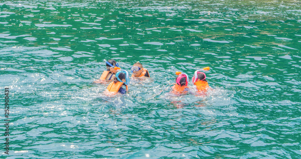 Group of people with life jacket snorkeling in sea