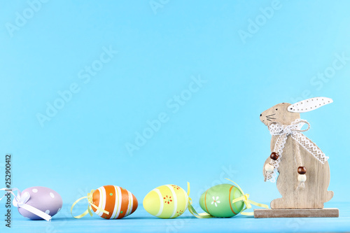 Wooden rabbit with easter eggs on blue background