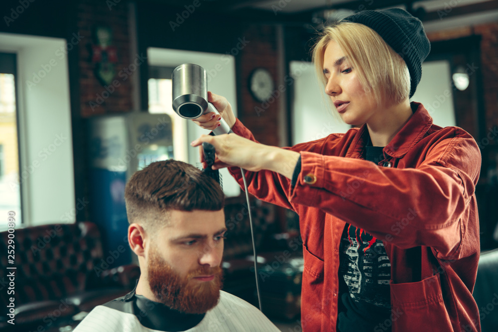 Client during beard shaving in barbershop. Female barber at salon. Gender equality. Woman in the male profession. Client during beard shaving in barbershop. Female barber at salon. Gender equality. Woman in the male profession.