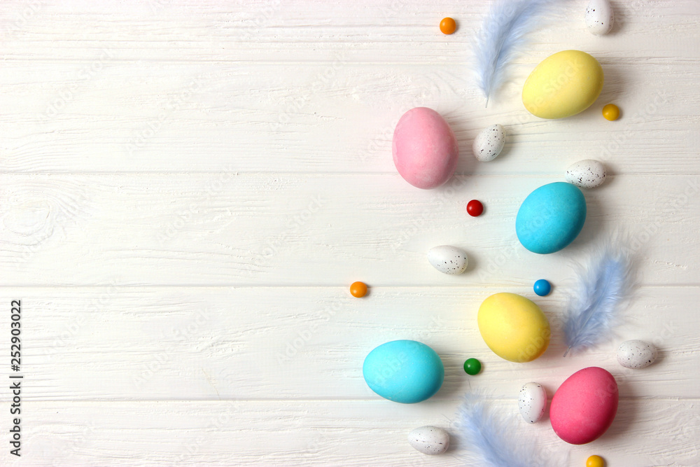  Easter composition of painted eggs and feathers on wooden background. Background for Easter, a place to insert text